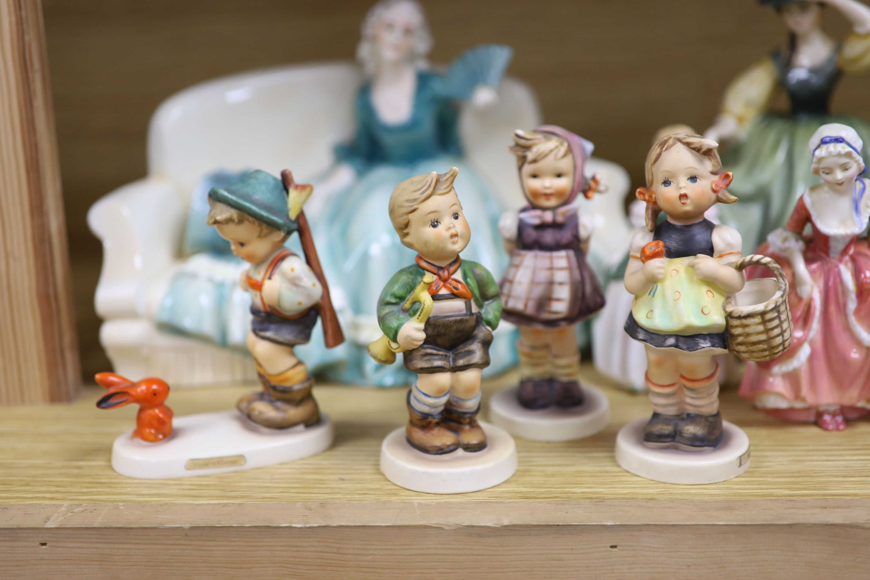 A collection of Hummel figures and Doulton ladies and a Katzhutte figure on a settee